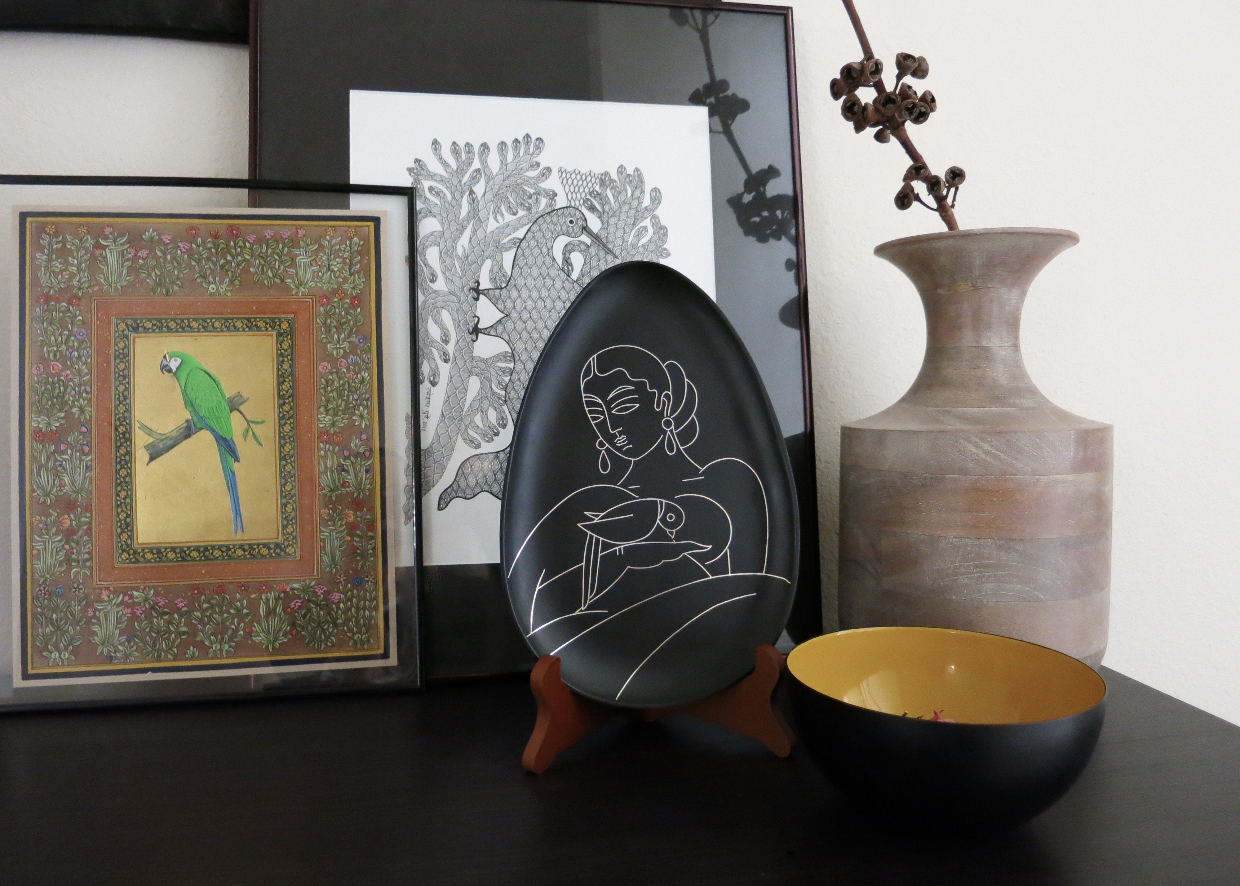 Decorative plates for home decor. Bidri metal and silver teardrop-shaped plate. Lady with a parrot. Design led, luxe, handmade home decor art objects. Handmade in India by Lai and Craft Stories